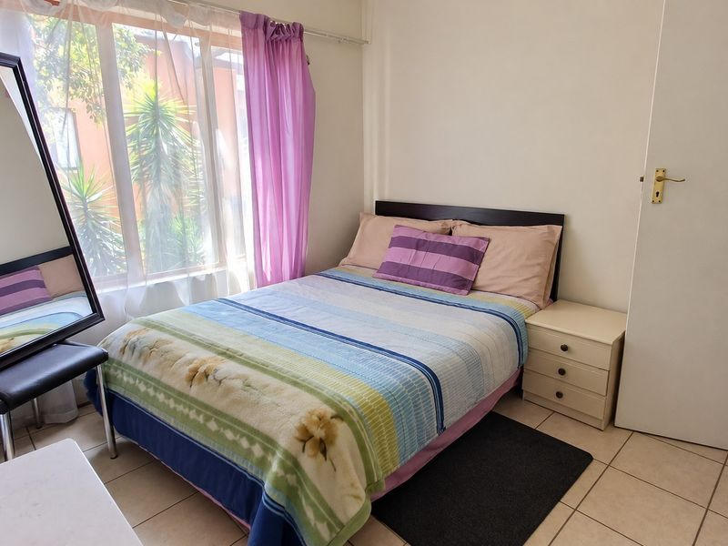 A functional bedroom featuring tiled flooring and a large window that allows for natural light.