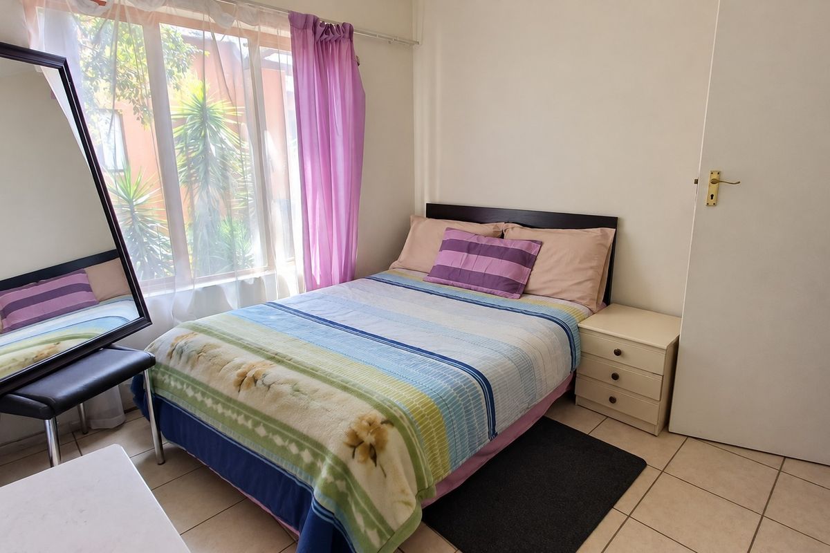 A functional bedroom featuring tiled flooring and a large window that allows for natural light.