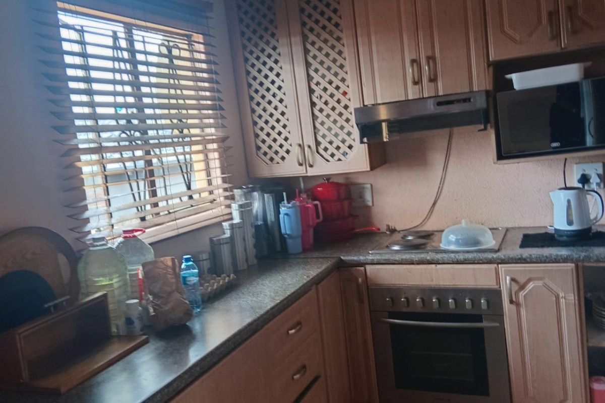 A functional kitchen featuring laminate cabinetry, built-in oven, extractor fan, and tiled flooring, offering a practical layout with ample counter space.