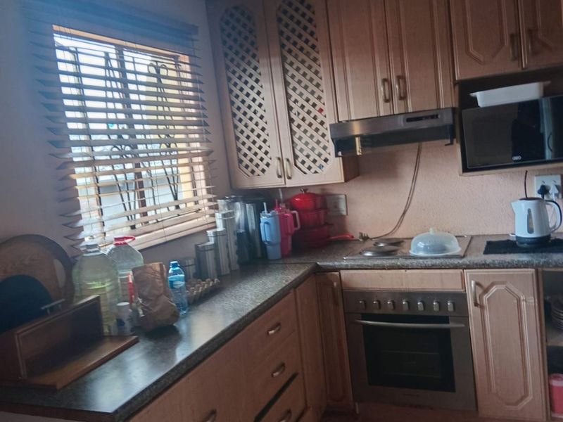 A functional kitchen featuring laminate cabinetry, built-in oven, extractor fan, and tiled flooring, offering a practical layout with ample counter space.