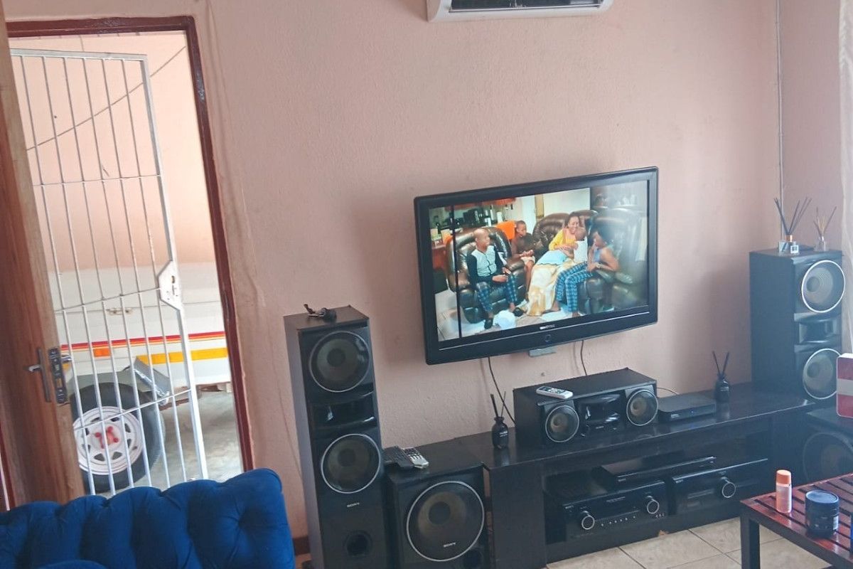 Living room featuring tiled flooring and a wall-mounted air conditioning unit, with direct access to an exterior area through a security gate.