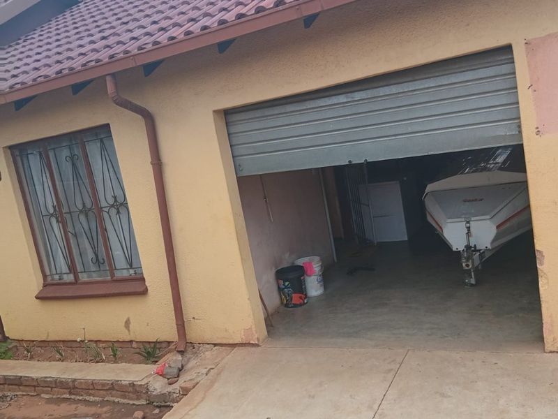Exterior view of a single garage with a roller shutter door, tiled roof, and security bars on the adjacent window.