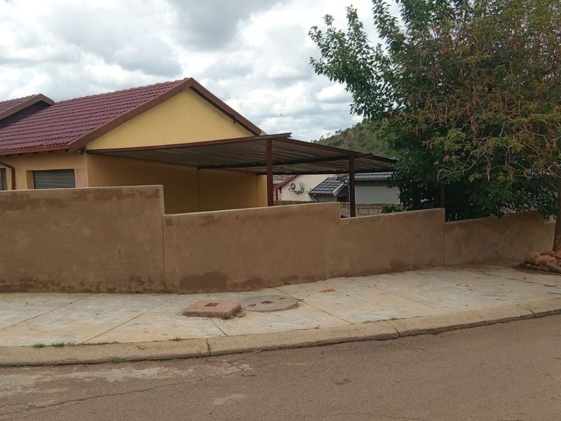 Front view of a residential property featuring a tiled roof, a carport, and a perimeter wall along the street sidewalk.