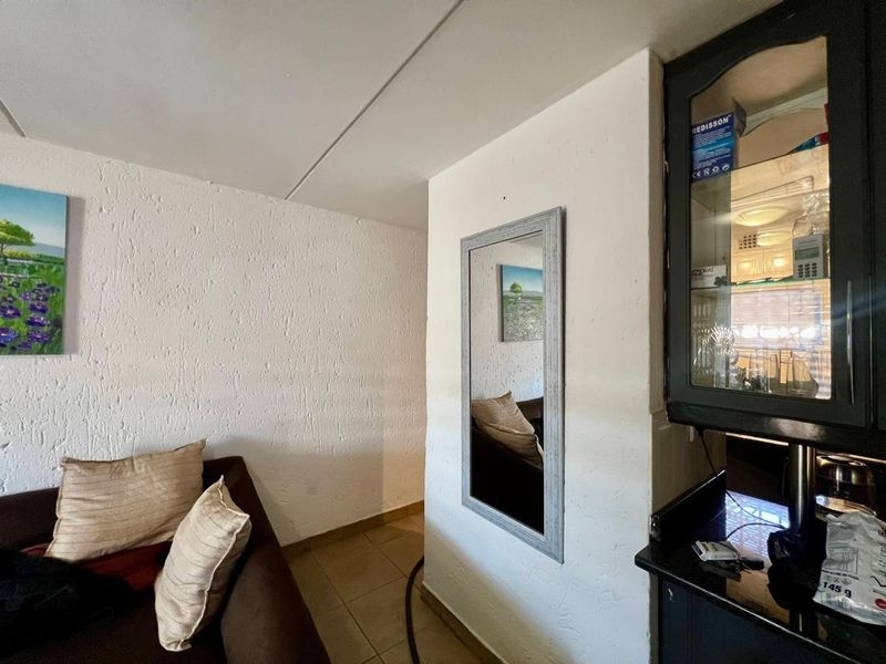 A living area featuring tiled flooring and a built-in display cabinet, offering a functional space with potential for modern updates.