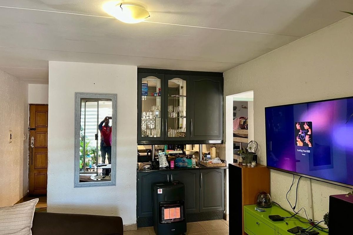 Living area featuring built-in cabinetry and tiled flooring, with visible ceiling water staining requiring attention.