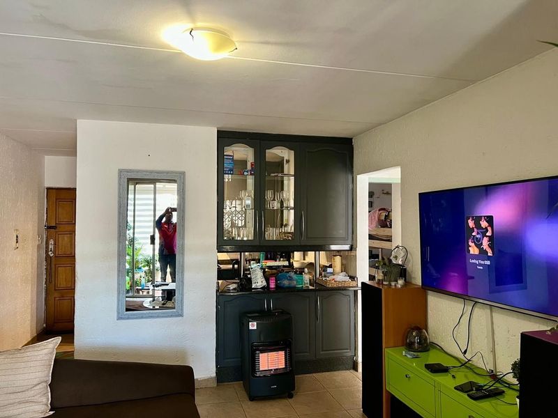 Living area featuring built-in cabinetry and tiled flooring, with visible ceiling water staining requiring attention.