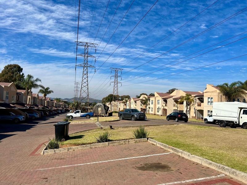 A view of the townhouse complex streetscape featuring paved driveways, landscaped lawns, and prominent overhead power infrastructure.