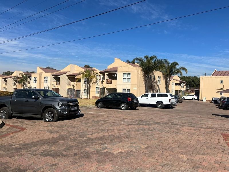 Exterior view of a multi-unit townhouse complex featuring a paved parking area and residential building facades.