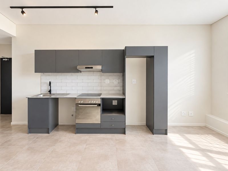 Modern open-plan kitchen featuring sleek grey cabinetry, subway tile backsplash, integrated oven and hob, and contemporary track lighting in a bright, tiled space.