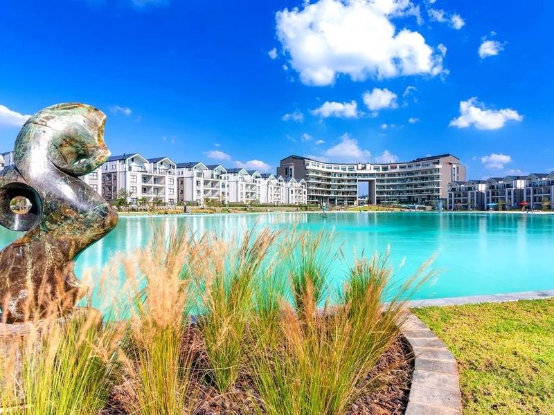 A scenic view of a large man-made lagoon surrounded by modern apartment buildings and well-maintained landscaped grounds.