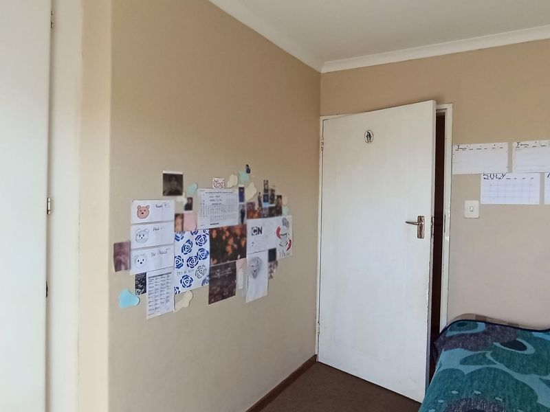 A standard bedroom interior featuring neutral wall paint, a single door, and carpeted flooring.