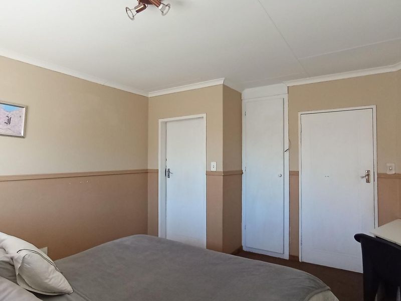 A bedroom featuring built-in cupboards, neutral wall tones with dado rail detailing, and standard ceiling finishes.