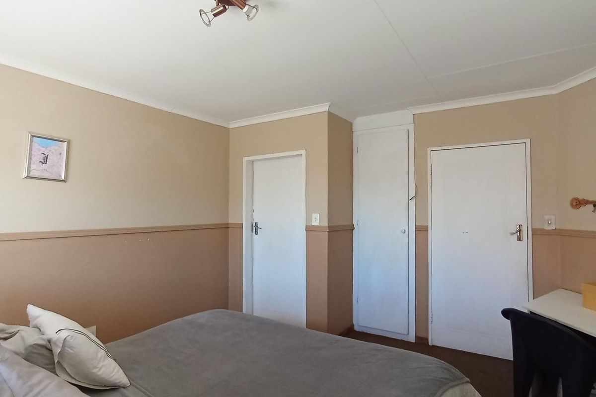 A bedroom featuring built-in cupboards, neutral wall tones with dado rail detailing, and standard ceiling finishes.