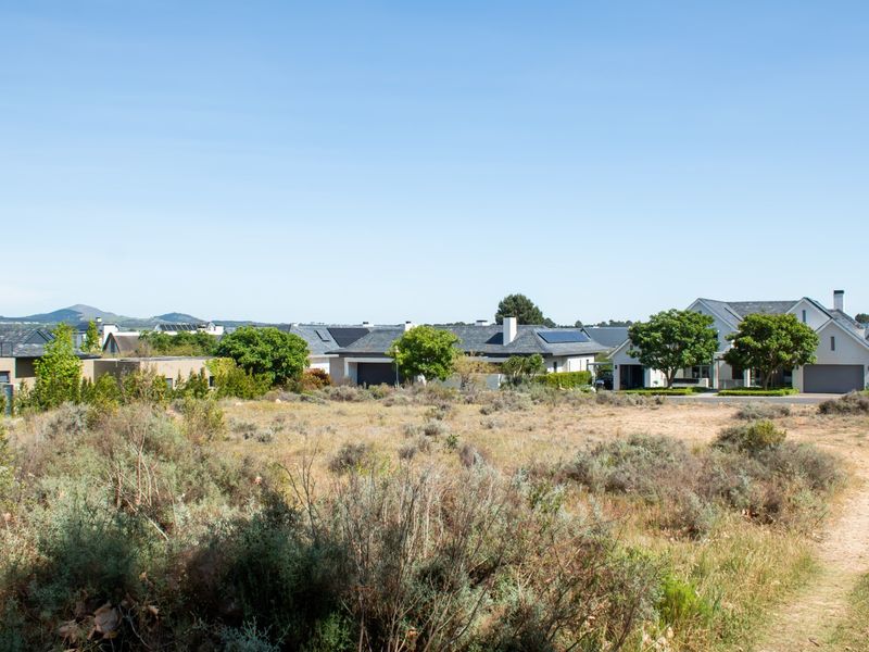 A view of a vacant residential plot with surrounding established homes and distant mountain scenery.