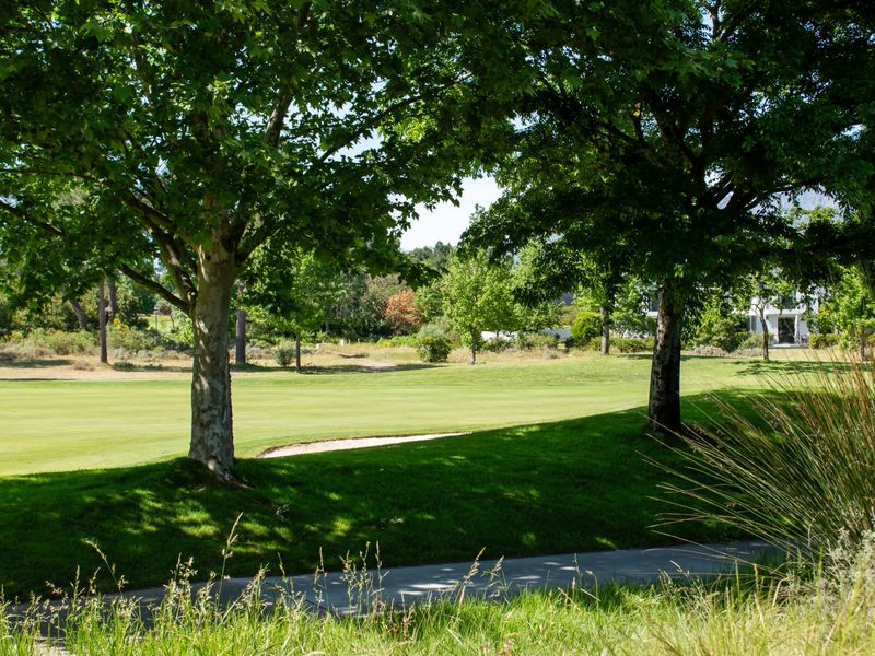 A scenic view overlooking a well-maintained golf course fairway with a sand bunker and mature trees.