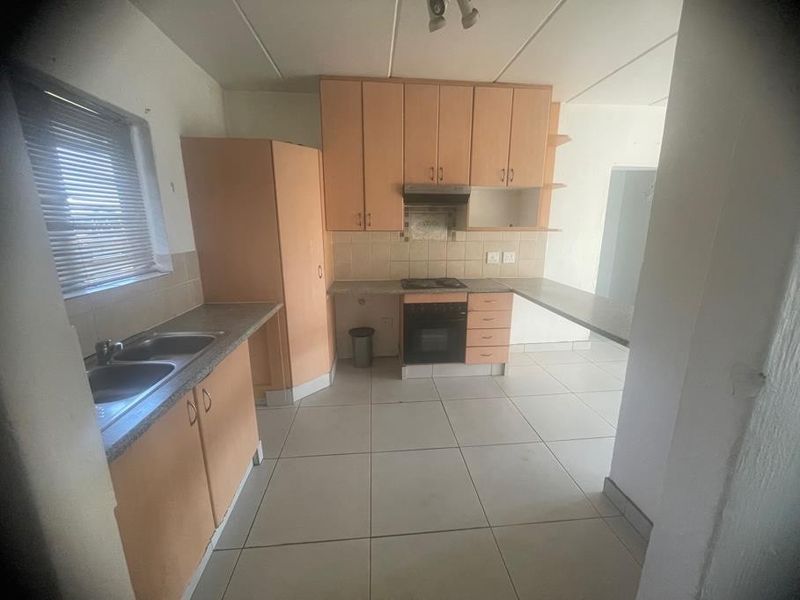 A functional kitchen featuring laminate cabinetry, built-in oven, hob, extractor fan, and double bowl sink with tiled flooring and backsplash.
