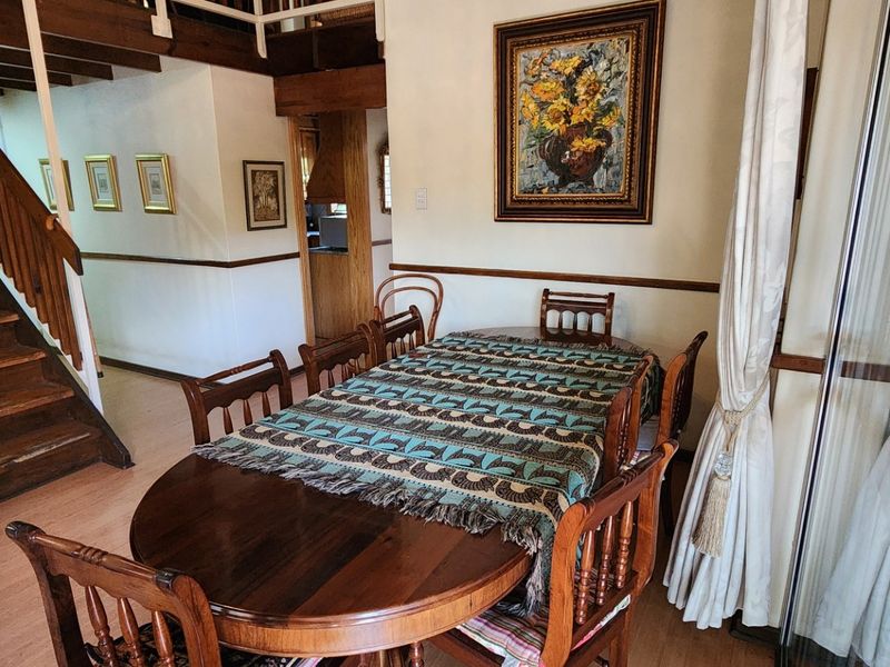 Dining area featuring laminate flooring, a wooden staircase with balustrade, and a sliding glass door leading to the exterior.