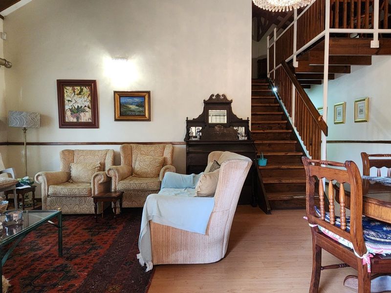 Spacious open-plan living and dining area featuring a vaulted ceiling, timber staircase with balustrade, and laminate flooring.