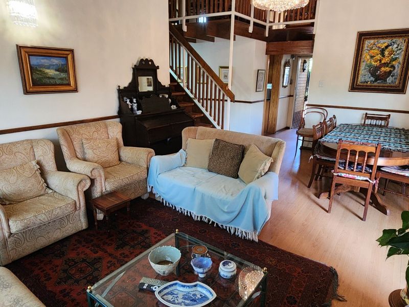 Open plan living and dining area featuring laminate flooring, a wooden staircase with balustrade, and access to the exterior via a sliding glass door.