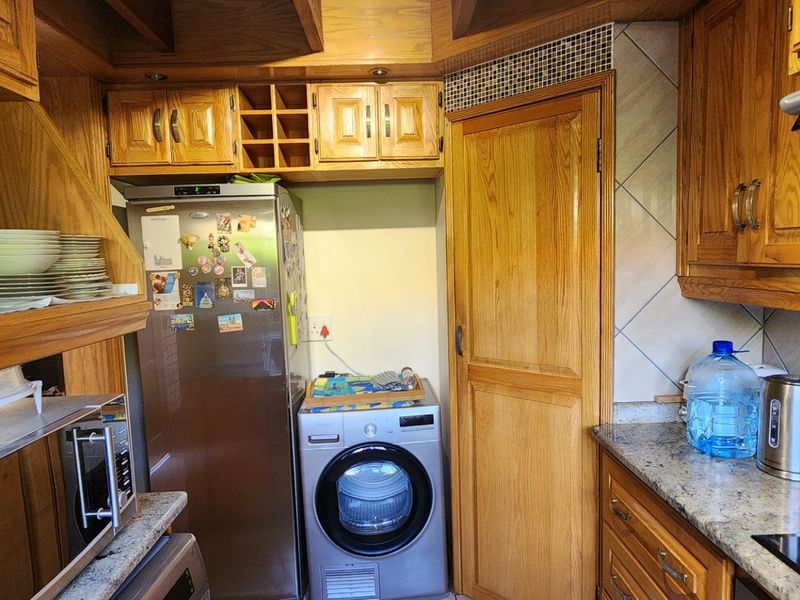 A functional kitchen featuring extensive wooden cabinetry, granite countertops, a tiled backsplash, and integrated appliances, offering a classic aesthetic with ample storage space.