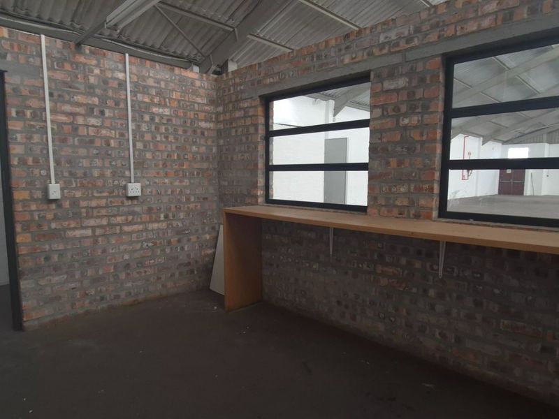 An industrial-style office space featuring exposed brick walls, metal-framed windows, and a built-in wooden counter, providing a functional workspace within the facility.
