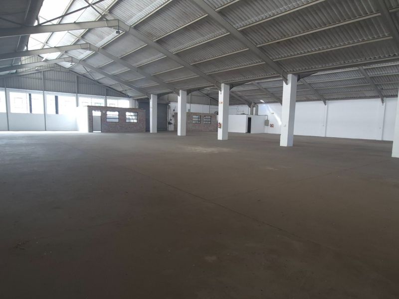 Spacious industrial warehouse featuring high ceilings, concrete flooring, and a robust steel portal frame structure, suitable for various storage or manufacturing operations.