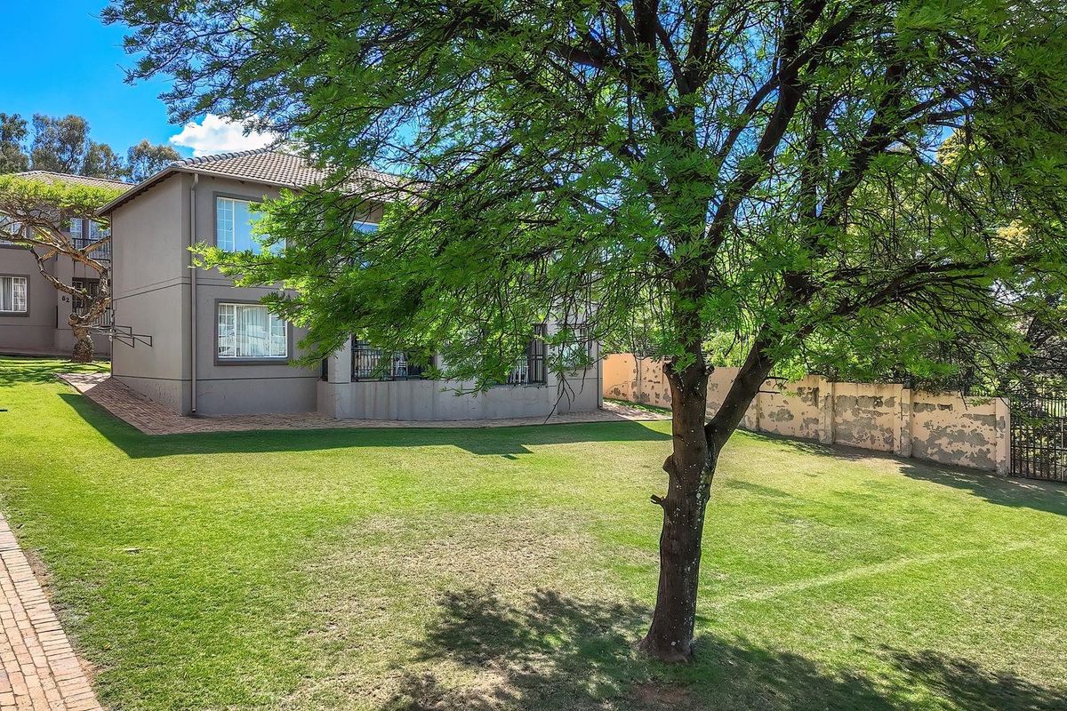 Rear view of the apartment building featuring a spacious lawn, paved walkways, and a perimeter boundary wall.
