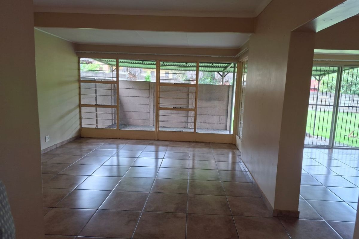 Spacious, empty living area featuring neutral tiled flooring and large windows that provide ample natural light and access to the outdoor space.