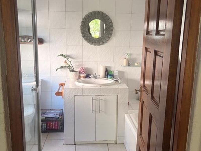 A functional bathroom featuring a tiled vanity with drop-in basin, a separate shower enclosure, and a built-in bathtub with classic tiled finishes.