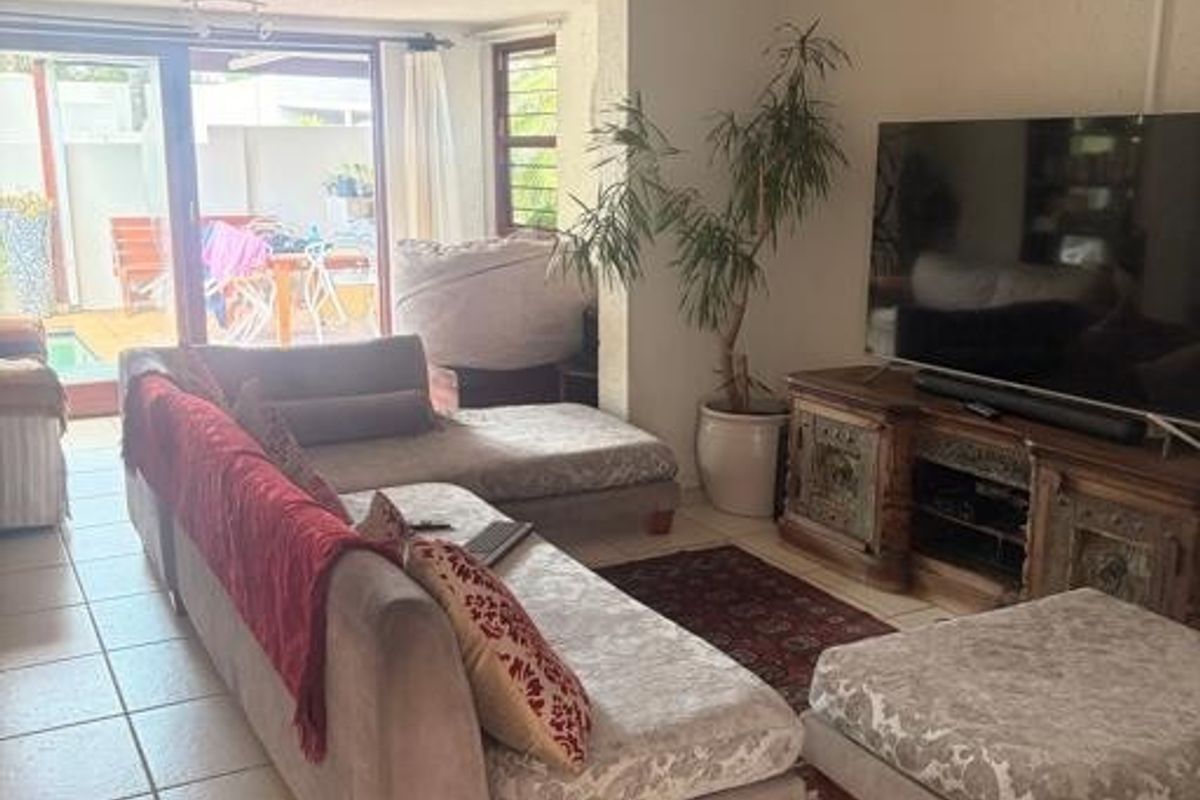 A living room featuring tiled flooring and a sliding glass door providing access to an outdoor patio area.