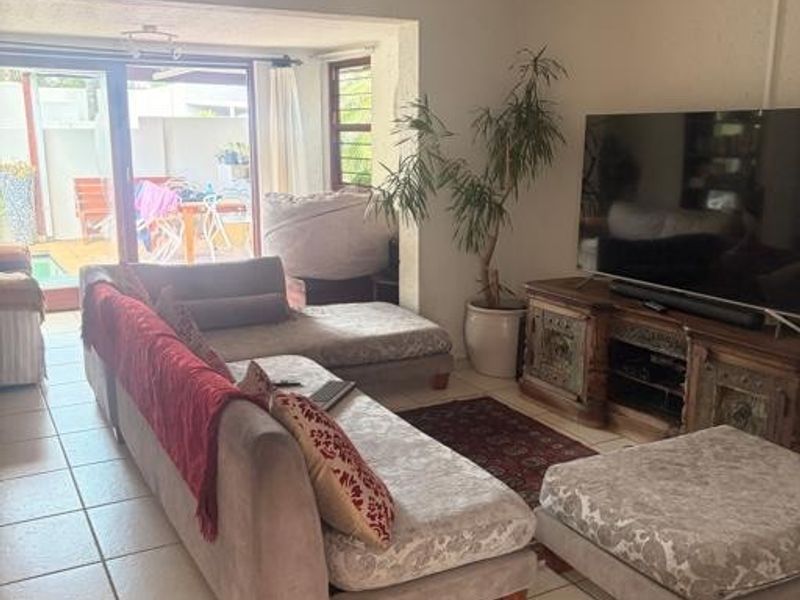 A living room featuring tiled flooring and a sliding glass door providing access to an outdoor patio area.