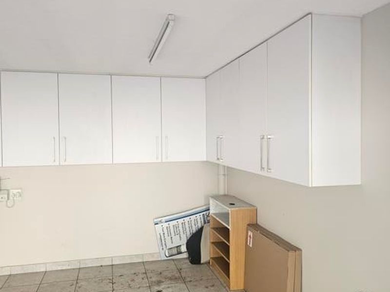 A functional garage space featuring extensive white built-in wall cabinetry and tiled flooring, providing ample storage potential.