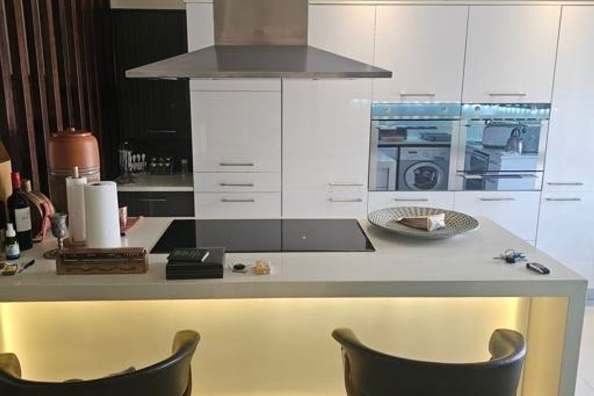 Modern kitchen featuring a central island with an induction hob, built-in appliances, sleek gloss cabinetry, and integrated under-counter lighting.
