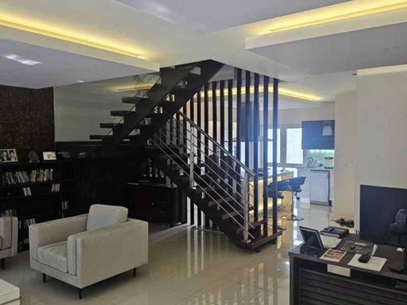 Spacious open-plan living area featuring a modern floating staircase with stainless steel balustrades, recessed ceiling lighting, and polished tiled flooring throughout.