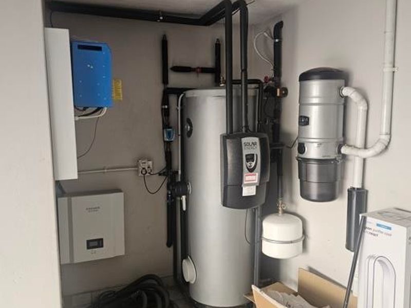 Utility area featuring a solar water heating system, central vacuum unit, and electrical inverter installation with tiled flooring.
