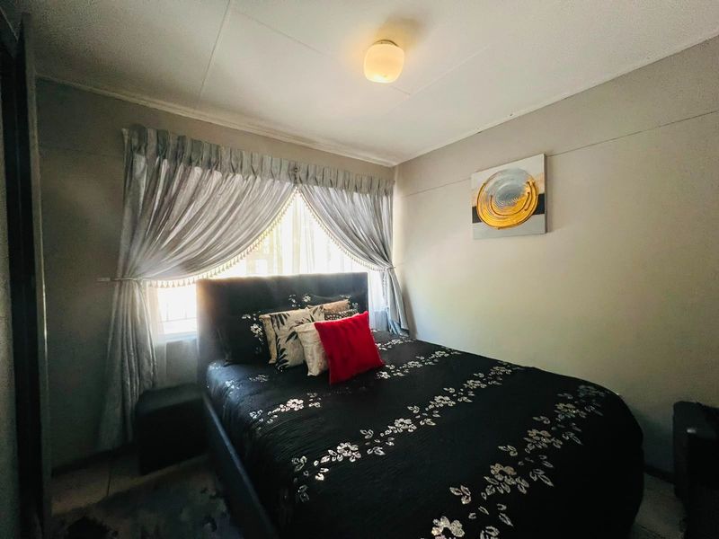 A standard bedroom featuring a central ceiling light fixture and a window with curtains.