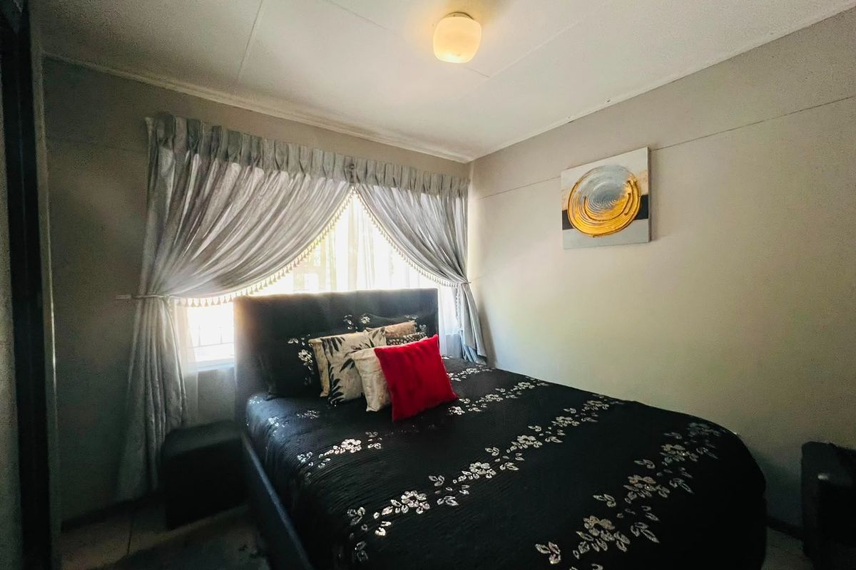 A standard bedroom featuring a central ceiling light fixture and a window with curtains.