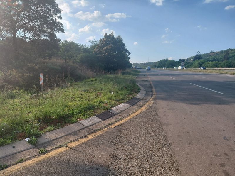A view of the public road infrastructure adjacent to the commercial land parcel, showing asphalt surfacing and concrete curbing.