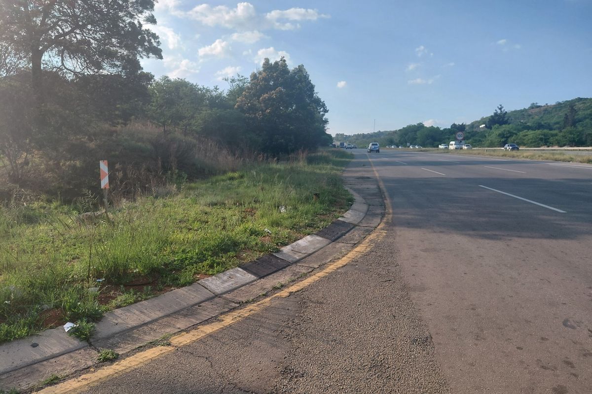A view of the public road infrastructure adjacent to the commercial land parcel, showing asphalt surfacing and concrete curbing.