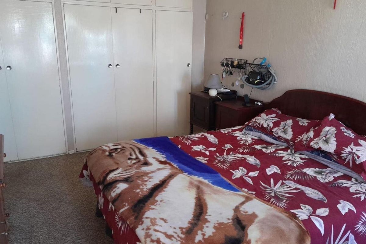 A bedroom featuring built-in cupboards and carpeted flooring, offering a functional space with potential for cosmetic updates.
