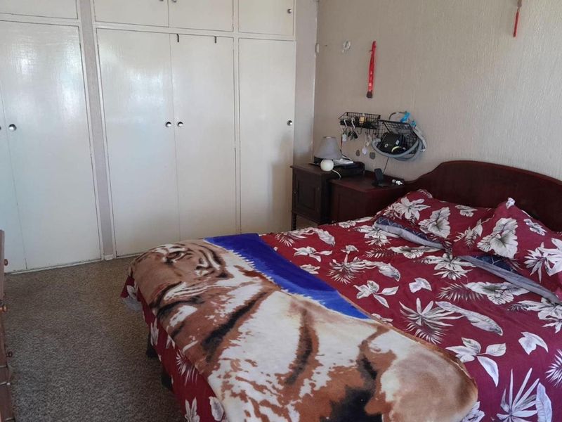 A bedroom featuring built-in cupboards and carpeted flooring, offering a functional space with potential for cosmetic updates.