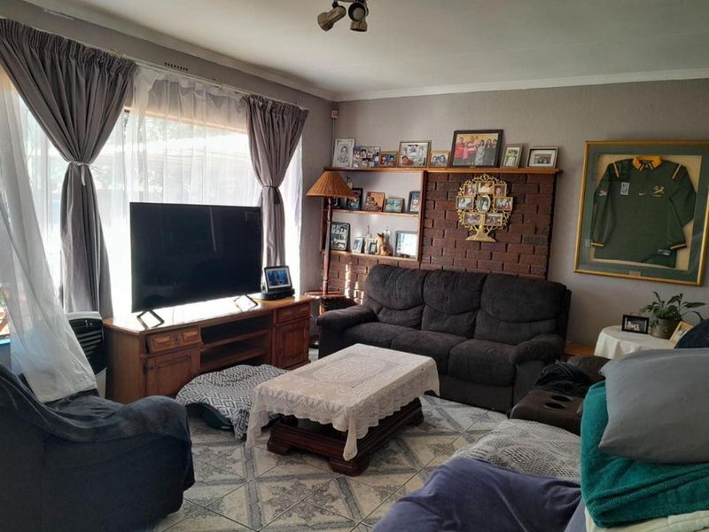 A comfortable living room featuring a brick accent wall with built-in shelving and tiled flooring, offering a cozy and functional space.