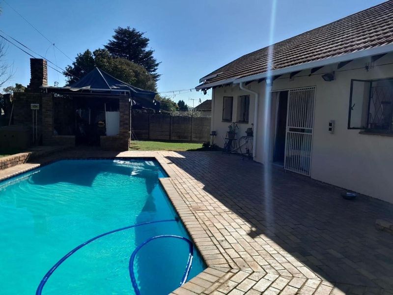 Outdoor entertainment area featuring a swimming pool, brick paved patio, and a brick built-in braai structure in the rear garden.