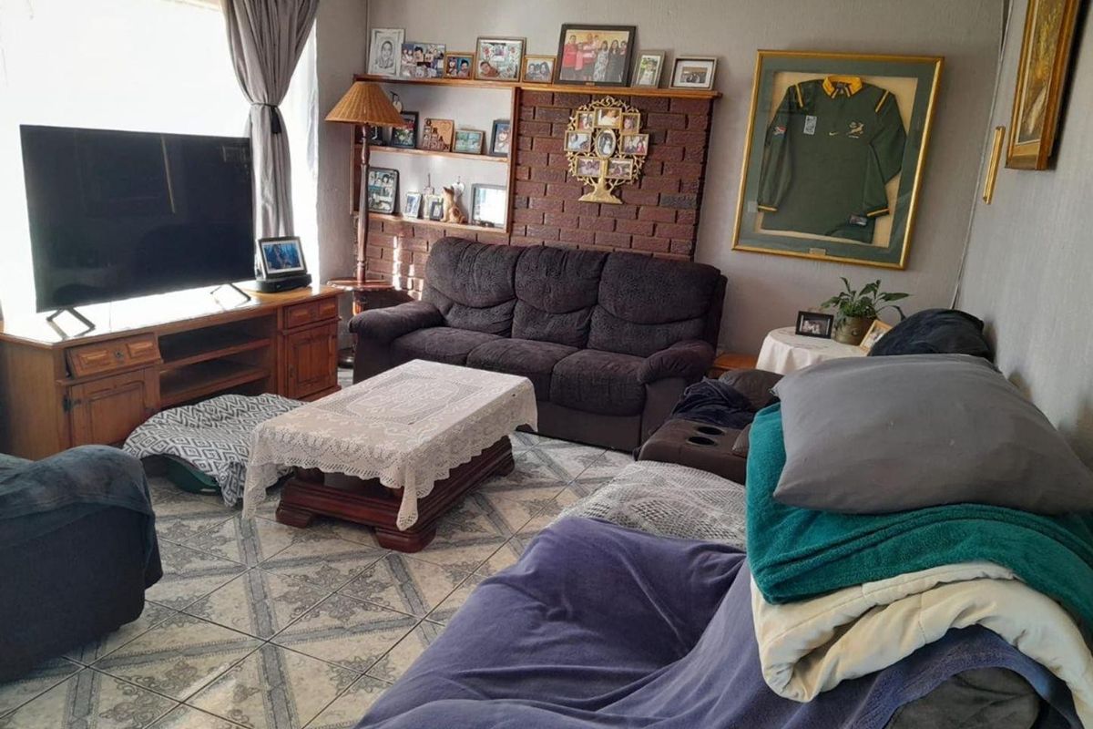 A living room featuring a brick accent wall with built-in shelving and tiled flooring, offering a functional space for relaxation.