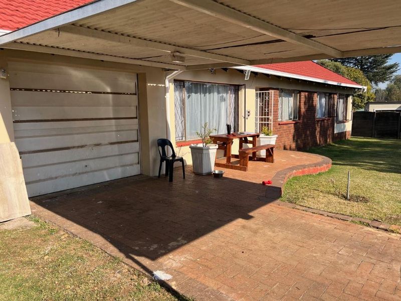 Covered patio area featuring brick paving and direct access to the garage and main house entrance, set against a brick exterior facade.