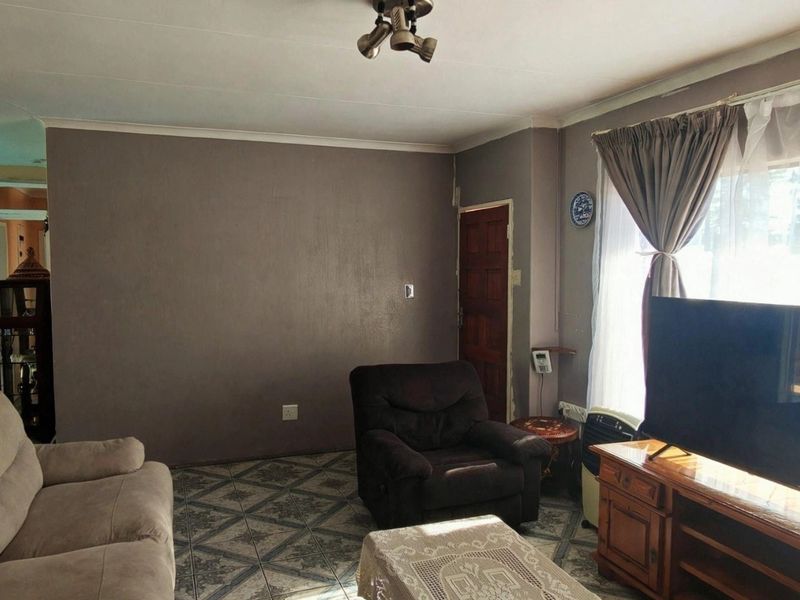 A living room featuring tiled flooring, coved ceilings, and natural light from a large window, providing a functional and comfortable living space.