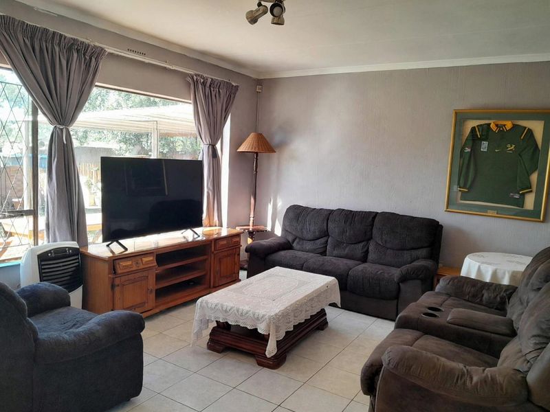 A comfortable living room featuring tiled flooring and a large window that allows for natural light.