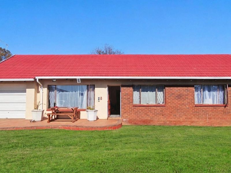 Front elevation of a single-story house featuring a red tiled roof, brick facade, and an attached single garage with a front patio area.
