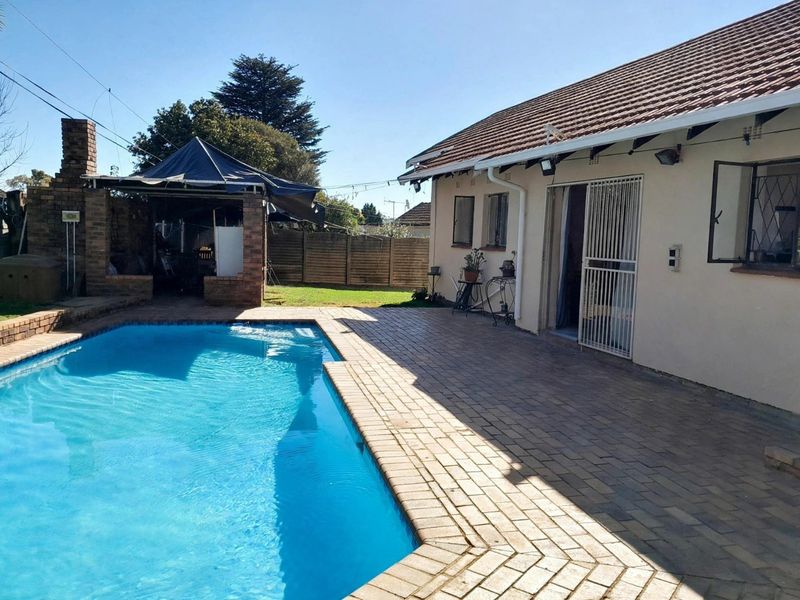 Outdoor entertainment area featuring a swimming pool, brick-paved patio, and a built-in brick braai structure, ideal for summer gatherings.