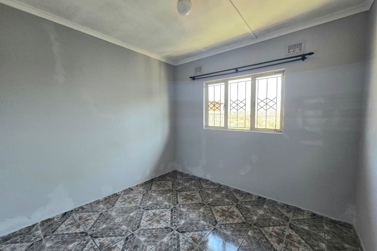 An empty bedroom featuring tiled flooring, security bars on the window, and a neutral wall finish, ready for personalization.